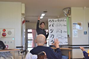 入居者がレクリエーション活動で文字盤を使った介護職員との交流風景